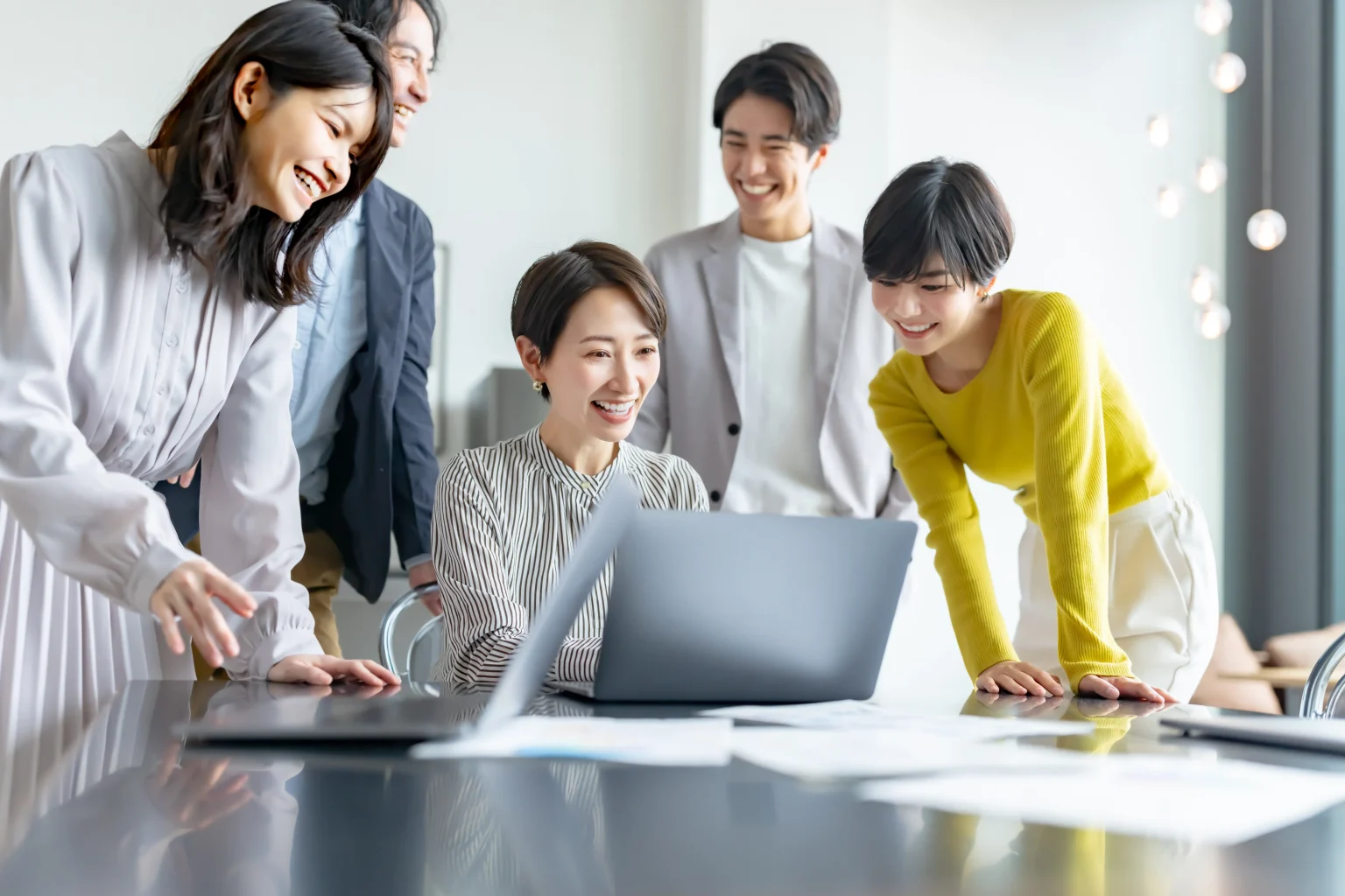 ノートPCを囲む笑顔のチーム